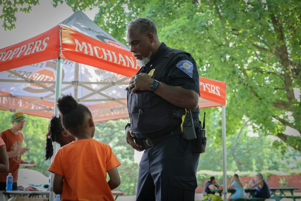 An officer speaks with a child at a cookout.