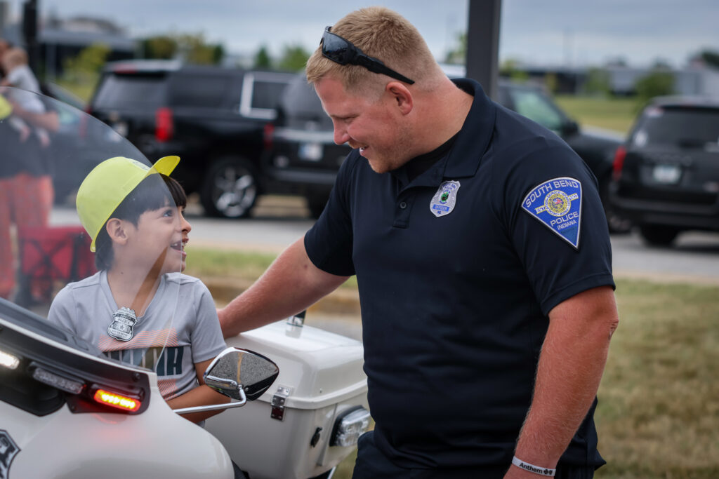 An officer helps a child onto a police motorcycle.