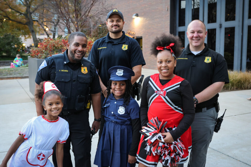 Officers pose with children at a trick-or-treat event.