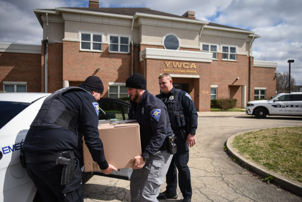 Three SBPD officers carrying a box into the YWCA building