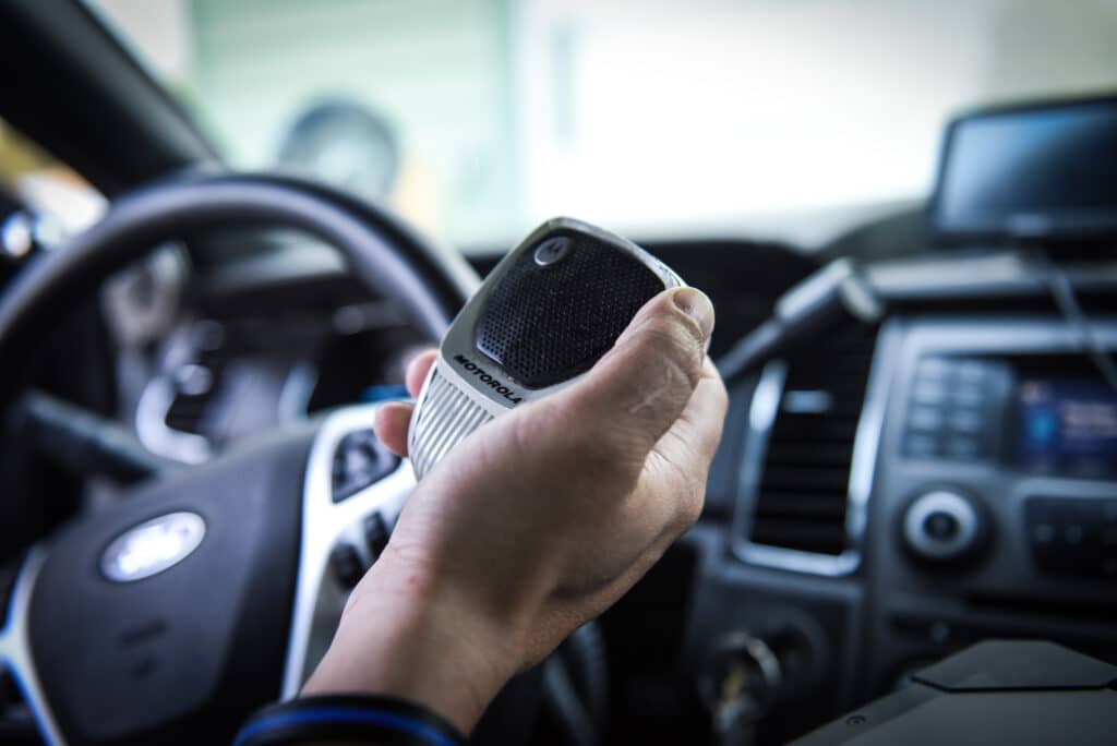 a hand holding a walkie talkie inside a car